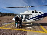 a group of people standing next to a helicopter